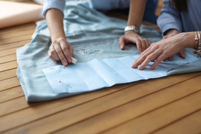 Hands of two cutters work with pattern,  concept of sewing business, small business and creativity