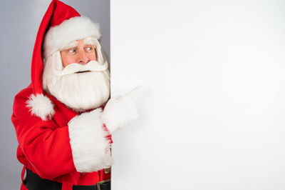 Portrait of woman wearing santa claus costume standing against white background