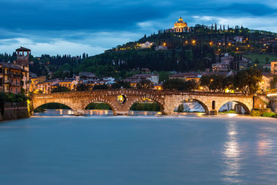 Arch bridge over river against buildings in city