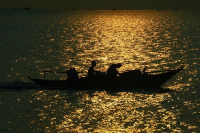 Silhouette people standing by sea against sky during sunset