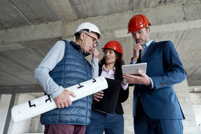 Thoughtful colleagues working with architect at site