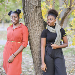 Portrait of smiling young couple standing against tree trunk