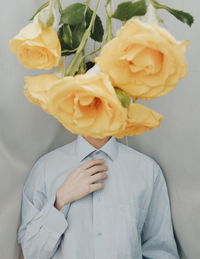 Close-up of rose flowers hanging over man face in background