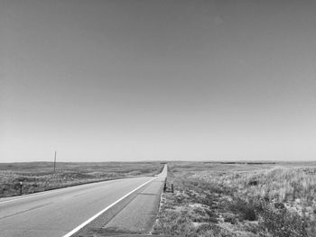 Empty road on field against clear sky