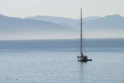 Sailboat upon the foggy mountainous horizon