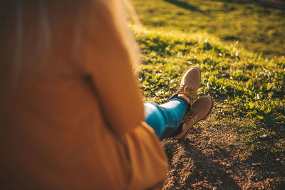 Low section of woman wearing shoes relaxing on field