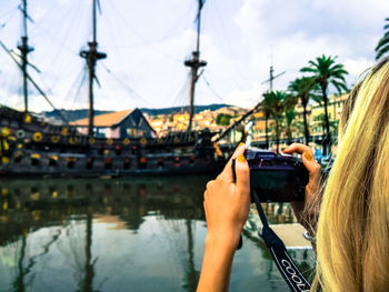 Midsection of woman using mobile phone against sky