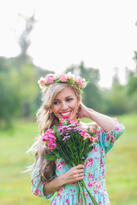 Portrait of smiling young woman against pink flowering plants