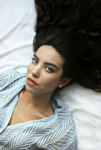 High angle portrait of beautiful woman lying on bed