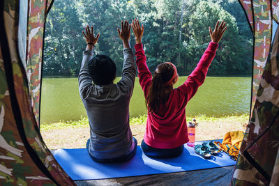 Rear view of people sitting on mat by lake