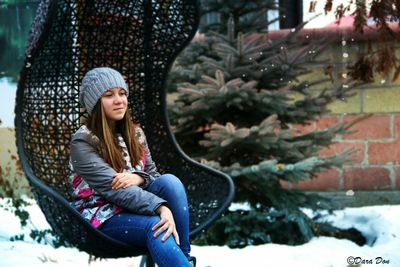 Woman sitting on snow covered tree