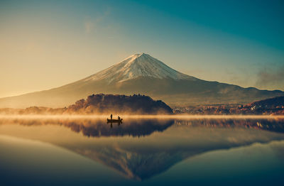 Scenic view of snowcapped mountains reflection in lake against sky during sunrise