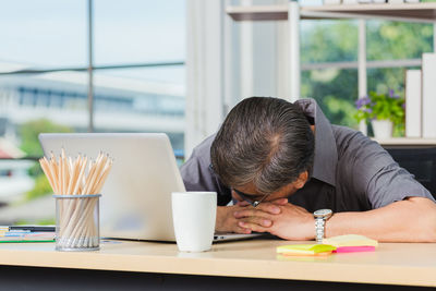 Rear view of man working on table at home