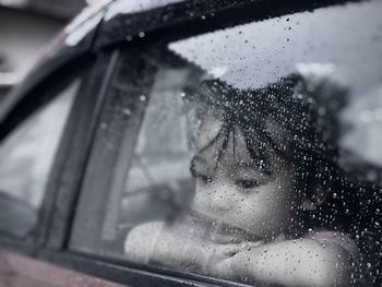 Portrait of woman seen through wet car windshield