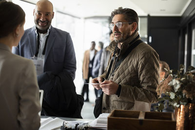 Businessman talking to receptionist at registering counter in conference center