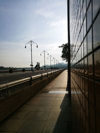 Empty road by street against sky during sunset