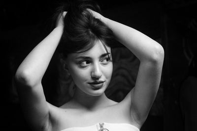 Portrait of young woman dancing against black background