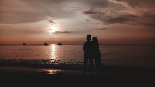 Silhouette man standing by sea against sky during sunset