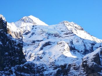 Scenic view of snowcapped mountains against clear blue sky