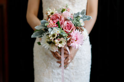 Midsection of woman holding rose bouquet