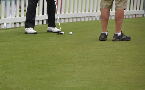 Low section of men playing golf on field