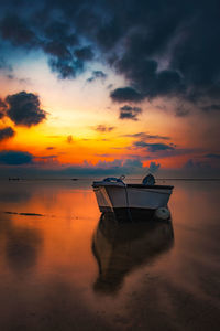 Boat moored on sea against sky during sunset