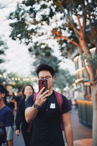 Man photographing with mobile phone standing outdoors