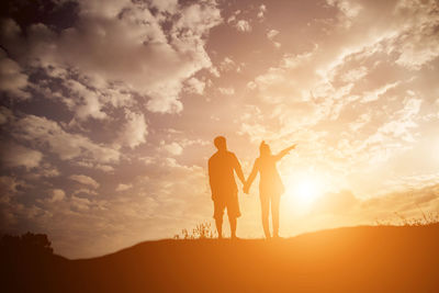 Silhouette friends standing against sky during sunset