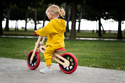 Rear view of boy riding push scooter on field