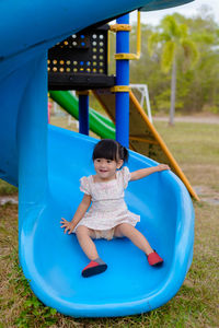 Cute girl on blue slide in playground