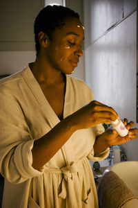 Young woman applying beauty product on face