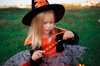 Portrait of young woman holding hat on field