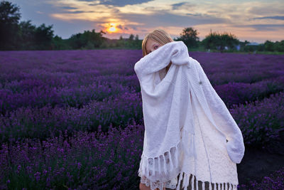 Teenage girl closes her face with white shawl and enjoys lavender field. summer travel, vacation