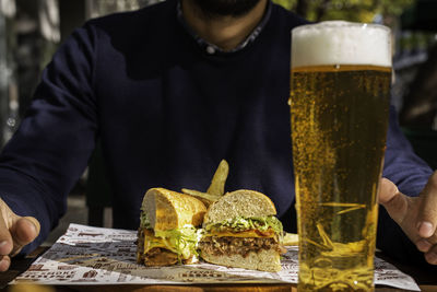 Midsection of man drinking glass on table