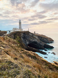 Lighthouse by sea against sky