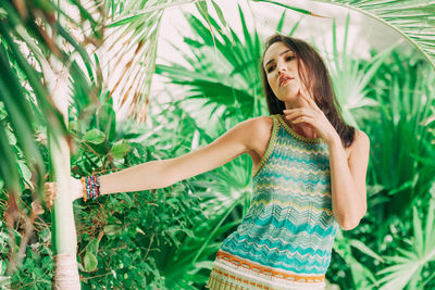 Thoughtful young woman standing by trees