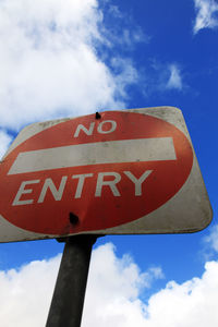 Low angle view of sign board against cloudy sky