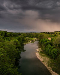 Scenic view of stream against stormy sky