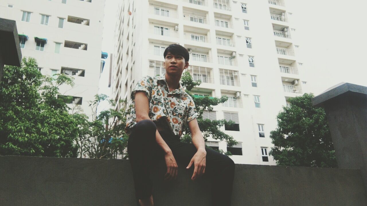 building exterior, architecture, built structure, one person, real people, young adult, building, plant, three quarter length, lifestyles, leisure activity, city, casual clothing, young women, day, nature, outdoors, sitting, standing, contemplation