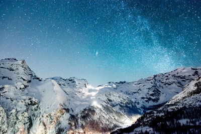 Scenic view of snowcapped mountains against stars at night