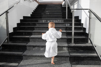 Rear view of boy walking on staircase in building