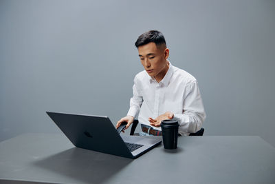 Young man using laptop at desk in office