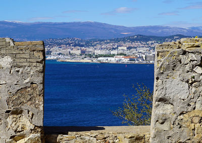 Sea by cityscape against sky