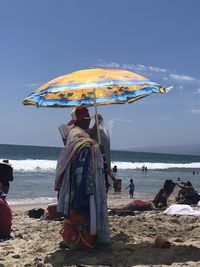 Rear view of people on beach against sky