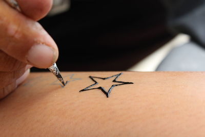 Close-up of hand making heena tattoo