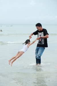 Full length of happy friends standing on beach against sky