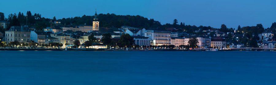 Illuminated buildings in city against clear sky at dusk