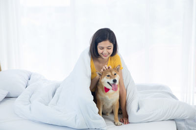 Full length of woman with dog on bed