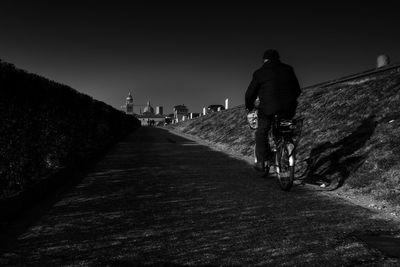 Rear view of man riding bicycle on road