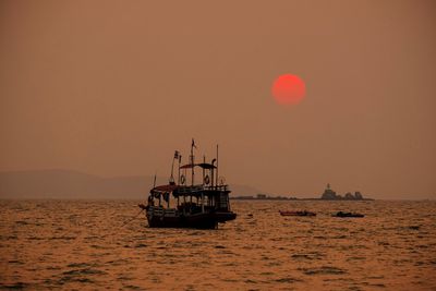 Boats in calm sea at sunset